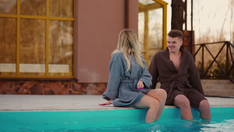 man-and-woman-are-resting-in-thermal-bath-in-recreation-complex-sitting-on-edge-of-outdoor-swimming-pool